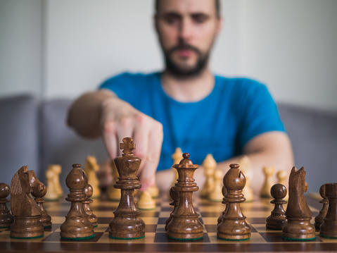 Unrecognizable caucasian man playing chess with wooden competition pieces