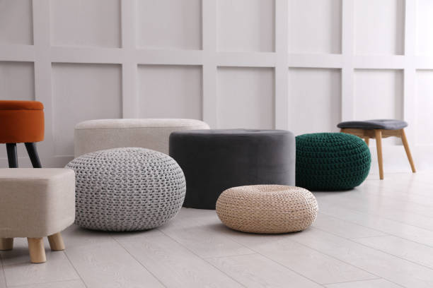 istock Different stylish poufs and ottomans near white wall 1408627875
