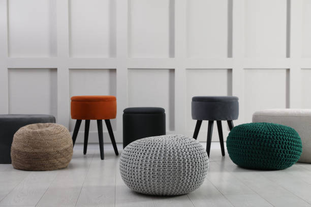 istock Different stylish poufs and ottomans near light wall 1408629593