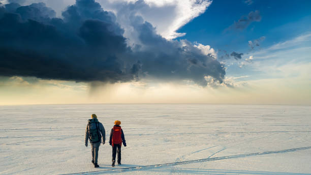 istock The two people with backpacks walking through the huge snow field 1408629873