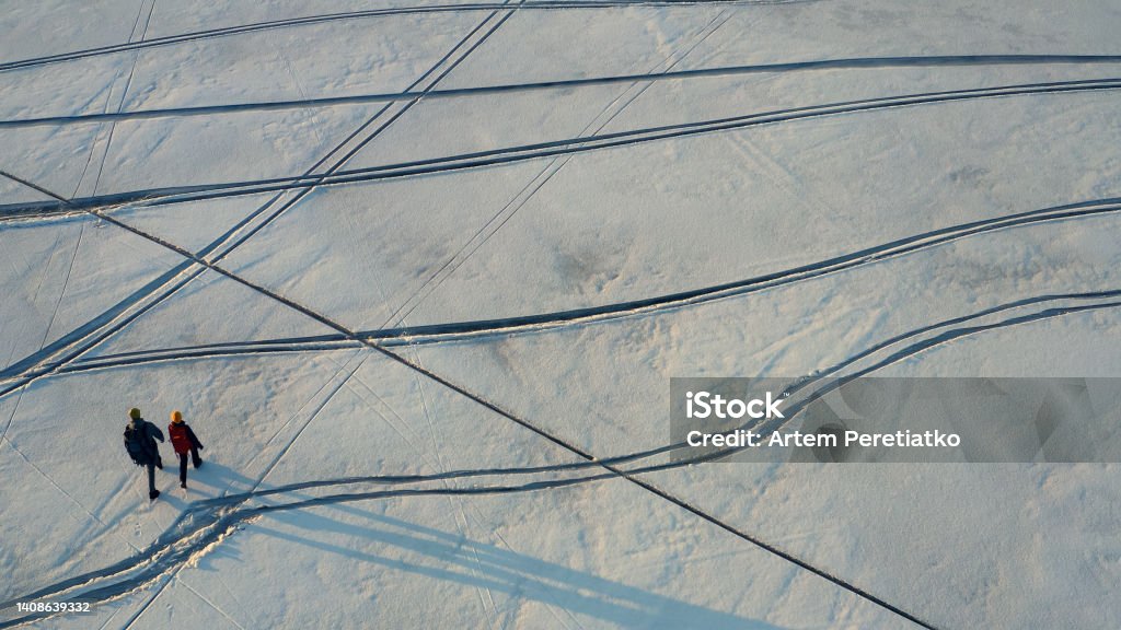 The upper view on two travelers walking through the icy field Couple - Relationship Stock Photo