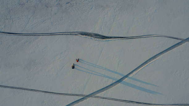 istock The upper view on two tourists walking through the snow field 1408639501