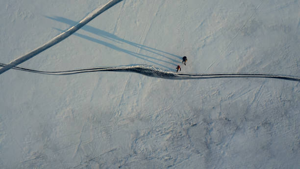 istock The upper view on two tourists walking through the snow field 1408639508