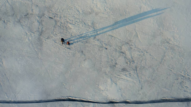 istock The upper view on two tourists walking through the snow field 1408639512