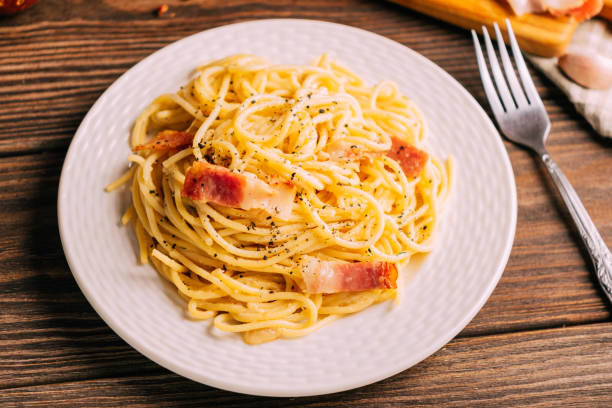 istock Classic italian pasta carbonara on white plate wooden tabletop, rustic style, Top view copy space 1408639620