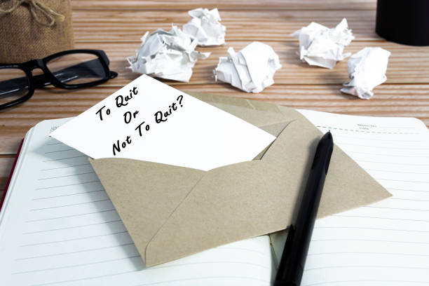 To quit or not to quit written on notepad with trash paper background. stock photo