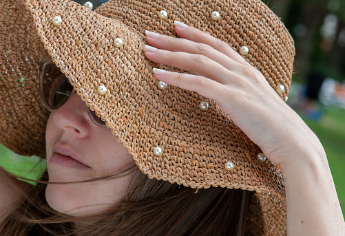 Young woman holding her hat with her beautiful hand