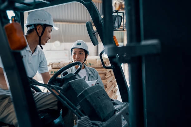 Mid adult female employer speaking with male employee in a shipping warehouse stock photo