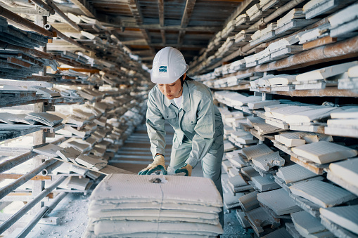 Mid adult woman checking condition of clay product in a warehouse before shipping