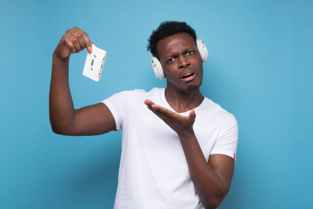istock African young man with a retro cassette does not know what to do with it. 1408643322