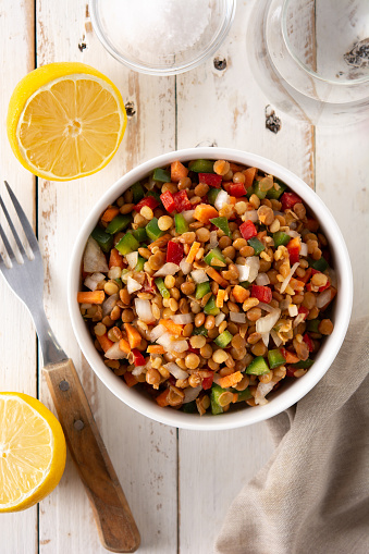 Lentil salad with peppers,onion and carrot in bowl on wooden table