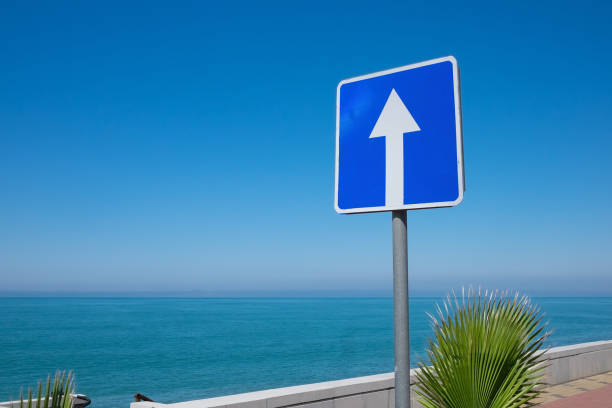 istock Square road sign with white arrow on blue sky background. 1408643598