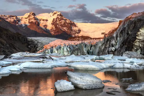 Warm sunlight across the ice and mountains of Svinafellsjokul glacier at sunset., southern iceland. Part of the larger Vatnajokull glacier, the largest ice cap in iceland.