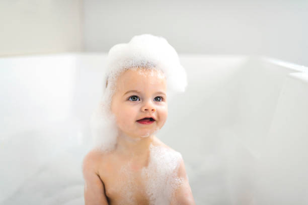 A Baby boy bathes in a bath with foam and soap bubbles