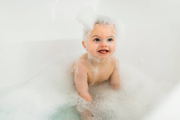 istock Baby boy bathes in a bath with foam and soap bubbles 1408645635