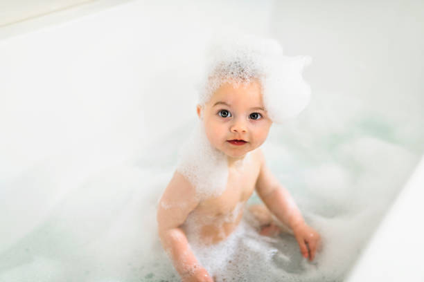 istock Baby boy bathes in a bath with foam and soap bubbles 1408645636
