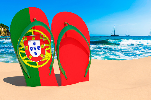 Flip flops with Portuguese flag on the beach. Portugal resorts, vacation, tours, travel packages concept. 3D rendering