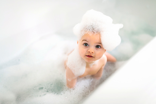 A Baby boy bathes in a bath with foam and soap bubbles