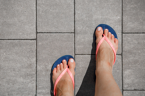 female feet in flip-flops on a tile