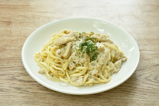 steamed spaghetti with white truffle mushroom cream sauce topping slice chicken breast on plate