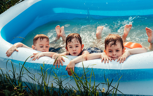 Happy children lie in the pool. Friends spend summer leisure together on a hot sunny day