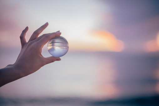 Focus of woman taking care of nature and the climate shown with nature encased in a luminous crystal ball hold by a womans hands with red nail polish