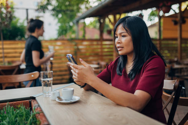 istock Thai woman resting in a coffee shop, using a mobile phone and drinking coffee 1408662115