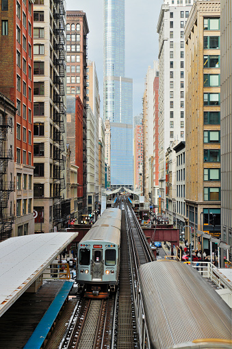 Day time Chicago cityscape featuring a commuter train traveling between stations on elevated railroad tracks surrounded by the buildings of the downtown district.