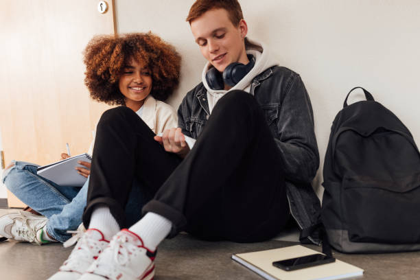 istock Two classmates preparing their assignments together while sitting on the floor 1408663693