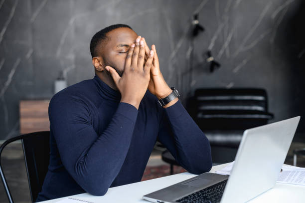 istock Tired African-American man with a laptop at office 1408664464