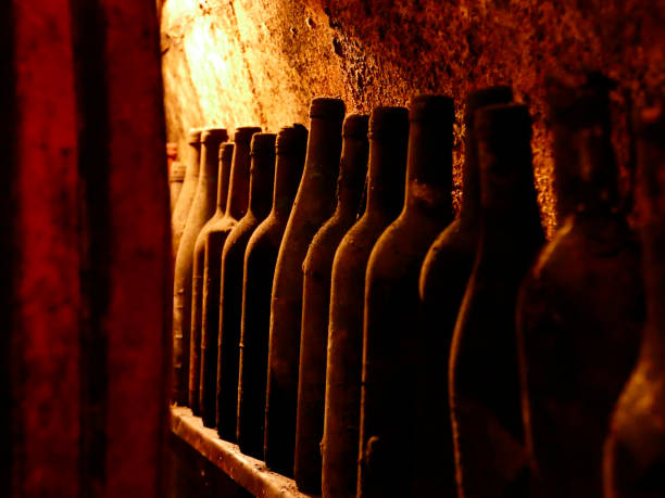 Old wine bottles a a barrel in a wine cellar stock photo