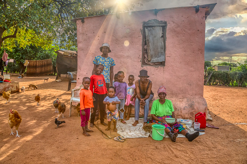 African family in the village, sitting in their yard, in front of the house