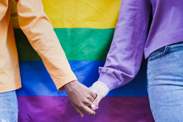 istock Lesbian couple holding hands with LGBT rianbow flag in background 1408674571