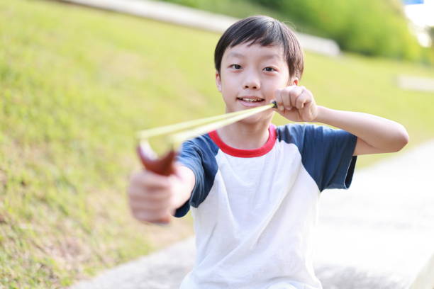 istock Young boy with slingshot shooting 1408674952