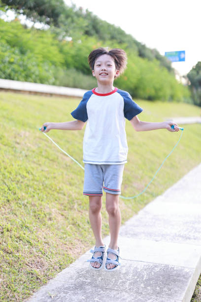 istock Little boy jumping rope on grass 1408674996