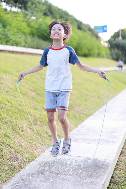istock Little boy jumping rope on grass 1408675013
