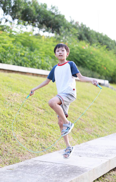 istock Little boy jumping rope on grass 1408675043