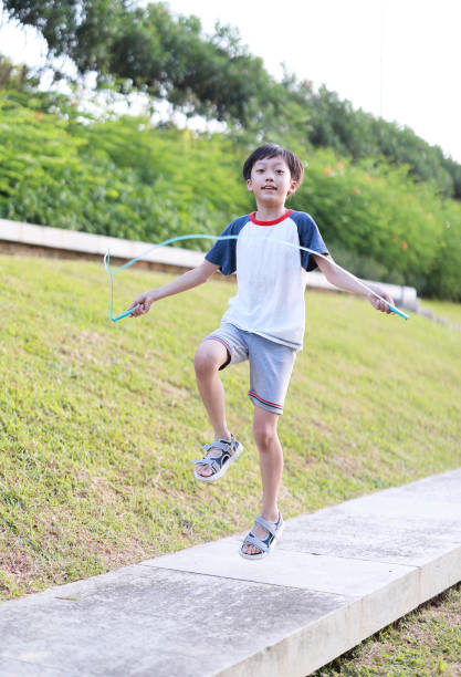 istock Little boy jumping rope on grass 1408675052