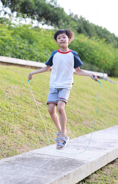 istock Little boy jumping rope on grass 1408675056