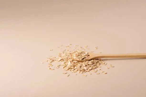 A minimalistic wooden spoon with natural oats. Front view.