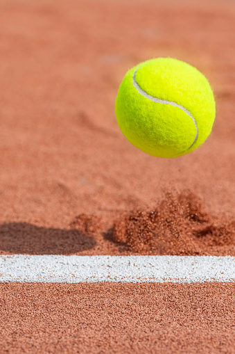 A close-up of a tennis ball in mid-air after hitting inside the baseline on a clay court for an ACE!