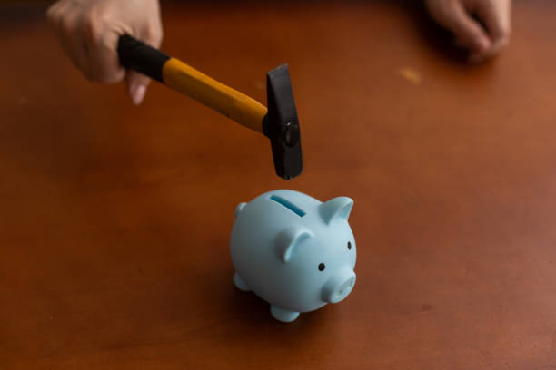 istock Man breaking piggy bank with hammer on table 1408680690