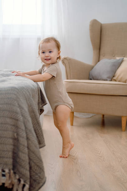 dziecko uczące się wstawać przez wsparcie. maluch stojący na palcach. chodzenie po palcach. kamienie milowe rozwoju. - baby toe zdjęcia i obrazy z banku zdjęć