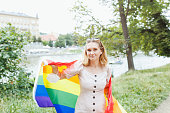 Young woman with LGBTQI pride rainbow flag on the street in the park. Pride Month concept