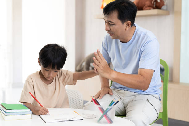 istock Asian little boy drawing on pages with colour pencils on table at classroom. Kid learning by drawing. Education concept 1408690805
