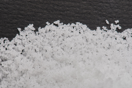 Industrial polystyrene granules white pile on black background
