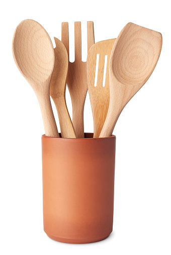 Set of wooden kitchen utensils, spoon, fork and spatula, in a terracotta container, isolated on white backgorund