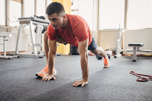 One man, fit young man warming up before training in gym alone.