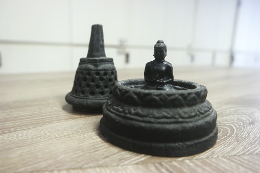 A miniature of stupa Borobudur with buddha inside it. Creates from black rock sculpture.
