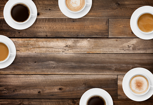 Coffee cups border on rustic wood background